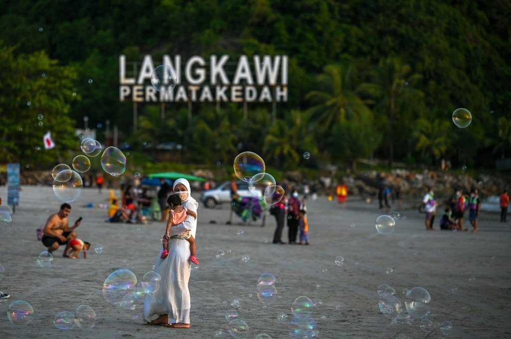 Pelancong bersiar-siar di Pantai Cenang di Langkawi pada 16 September 2021 selepas pulau itu membuka semula pintunya kepada pelawat selepas perintah kawalan pergerakan dilonggarkan. Gambar: AFP