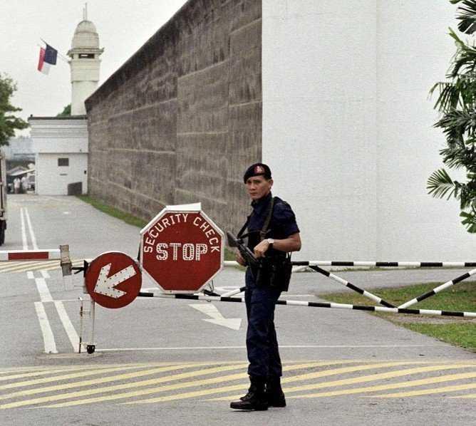 Seorang pengawal penjara bersenjata api berdiri di pintu masuk Penjara Changi di Singapura. Gambar: AFP