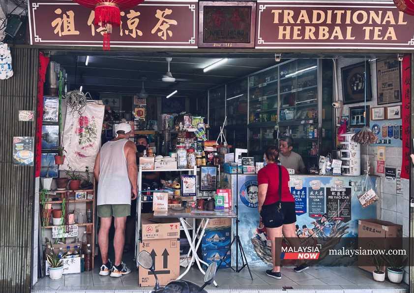 Customers stop to enquire at a traditional herbal tea shop near the Kuching city centre in Sarawak. 
