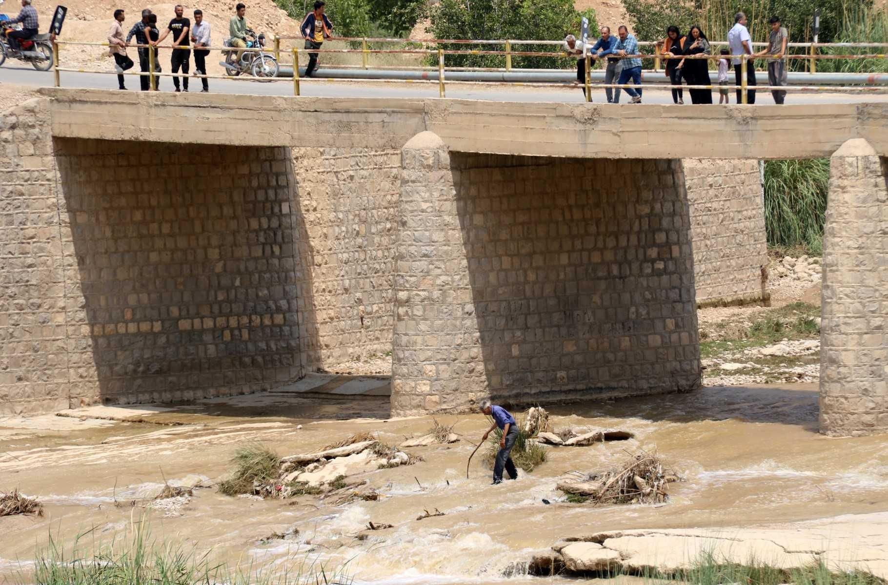 A picture obtained by AFP from the Iranian news agency Tasnim on July 23 shows people standing on a bridge above a river, after flooding caused by heavy rainfall in southern Iran's Estahban county, that reportedly killed at least 22. Photo: AFP