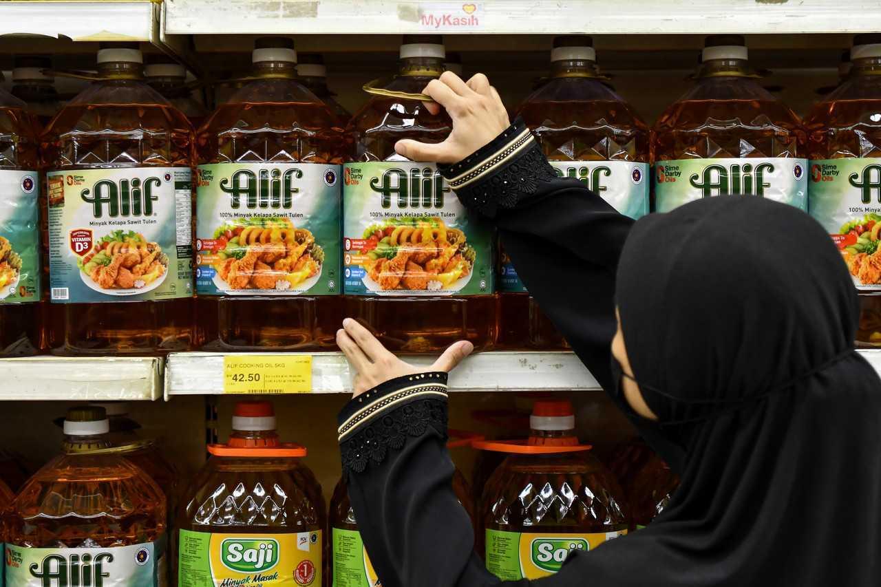 A worker arranges bottles of cooking oil on a shelf at a mart in Kuala Terengganu. Photo: Bernama