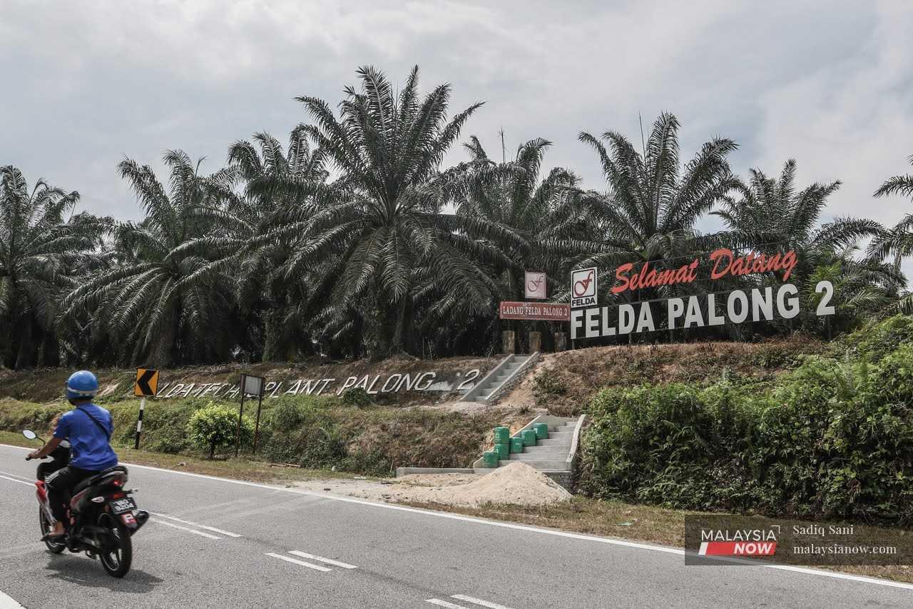 A motorcyclist rides past the entrance of the Felda Palong Dua settlement in Gemas, Negeri Sembilan.