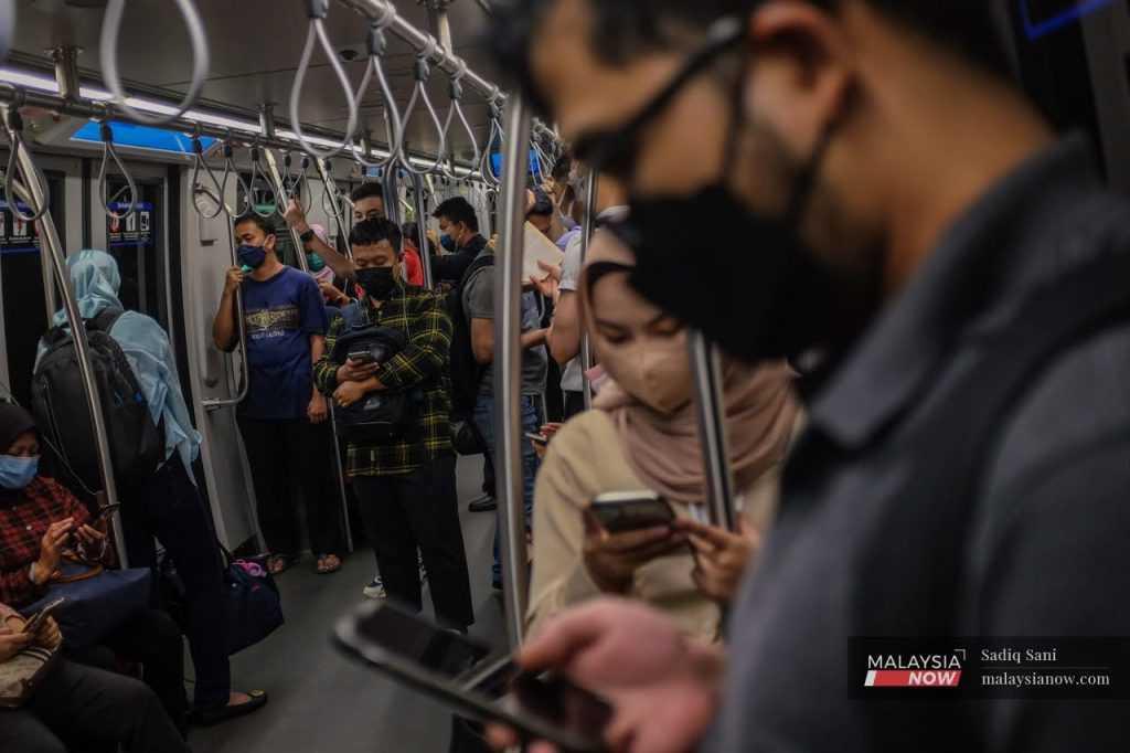 Commuters in Kuala Lumpur wearing face masks to curb the spread of Covid-19 take an LRT home after work.