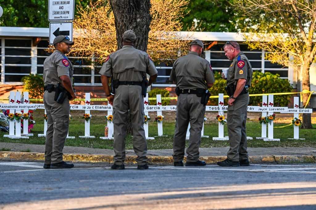Police officers stand near a makeshift memorial for the shooting victims at Robb Elementary School in Uvalde, Texas, on May 26. Photo: AFP