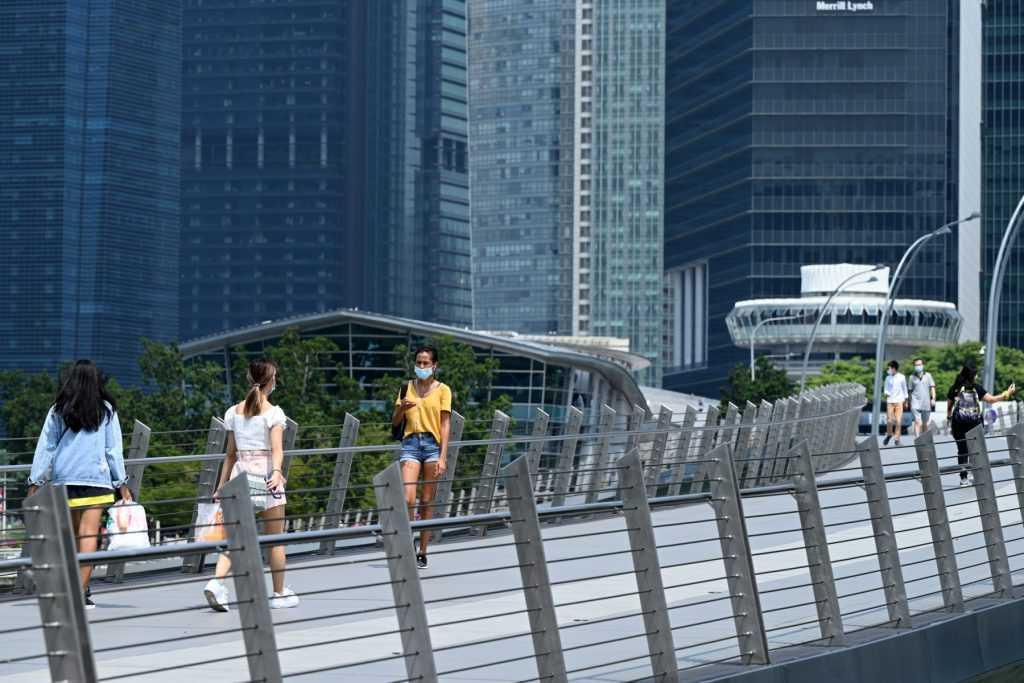 People walk along a pedestrian bridge at the financial business district in Singapore on June 25, 2021. Photo: AFP
