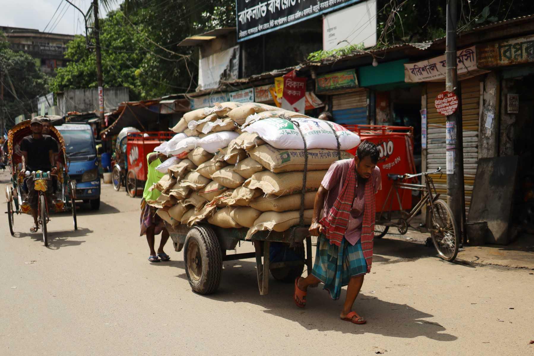 A labourer pulls a handcart loaded with sacks of grains along a street in Dhaka on June 22. Photo: AFP