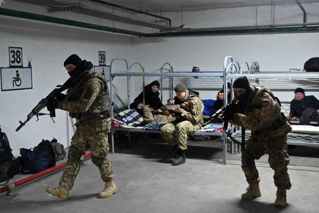 A soldier of the Territorial Defence Forces of Ukraine, the military reserve of the Armed Forces of Ukraine, eats his lunch while others training in an underground garage that has been converted into a training and logistics base in Kyiv, on March 11, 2021. Photo: AFP