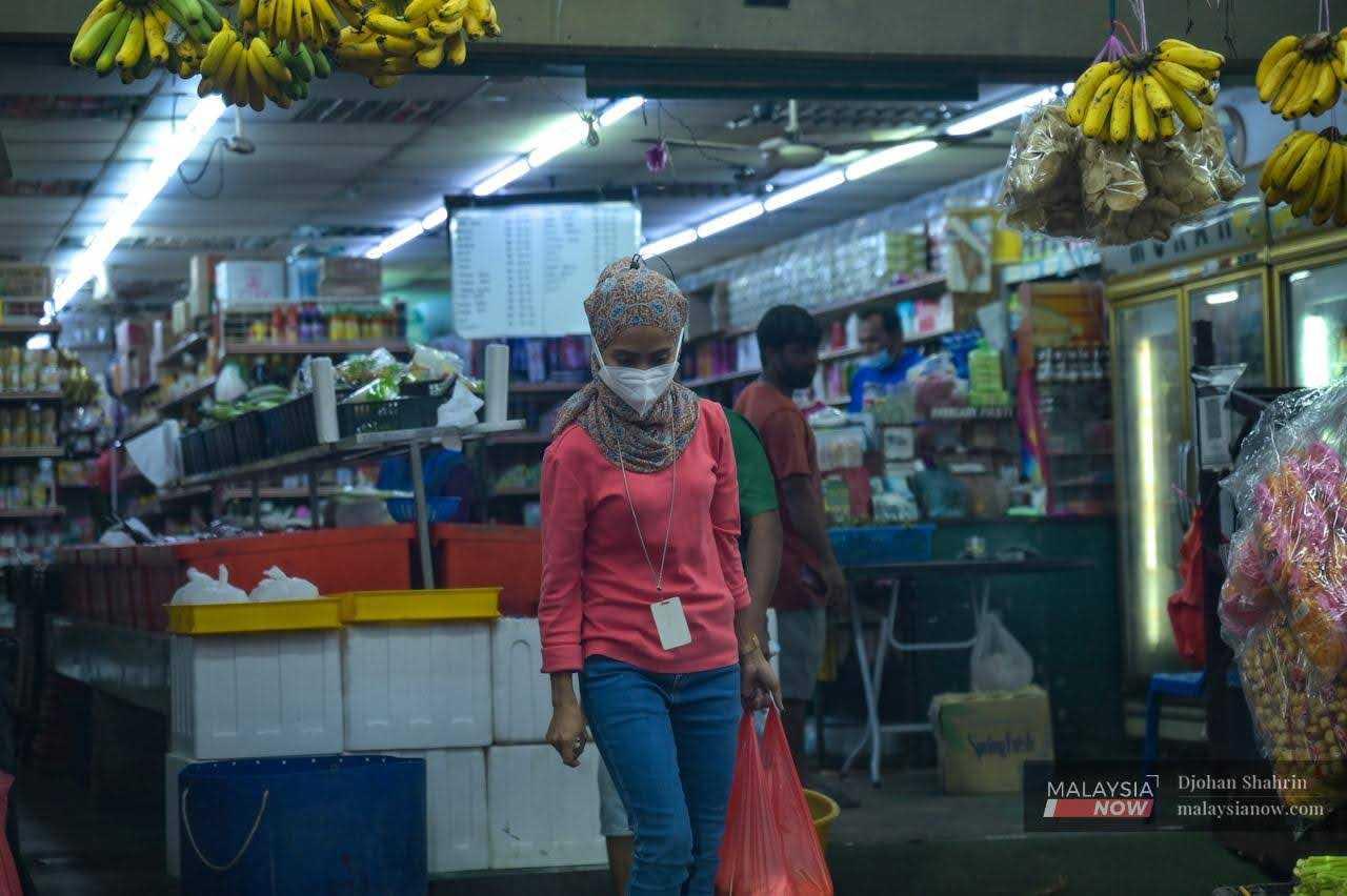 A woman leaves a sundry store after picking up some necessities in Tasik Tambahan, Ampang in Selangor. 