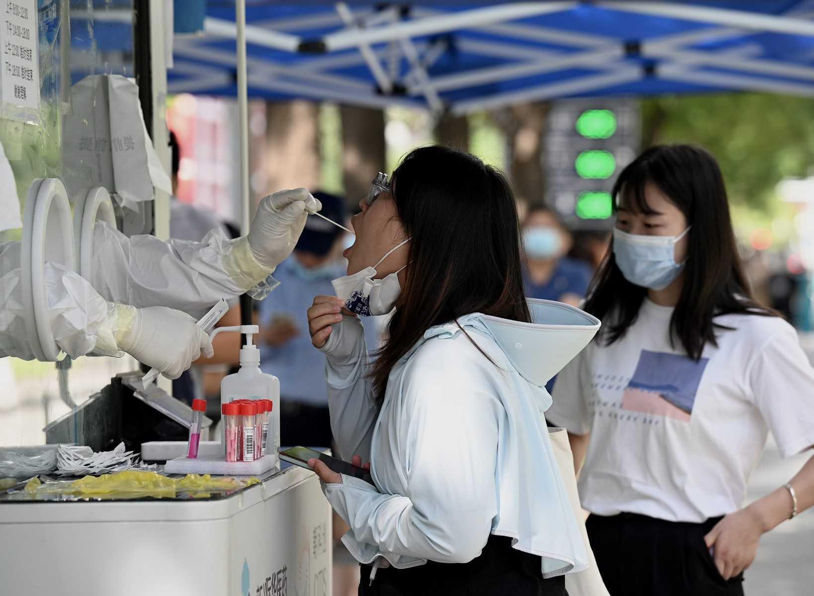 A health worker gets a swab sample from a woman to be tested for Covid-19 at a swab collection site in Beijing on July 13. Photo: AFP 