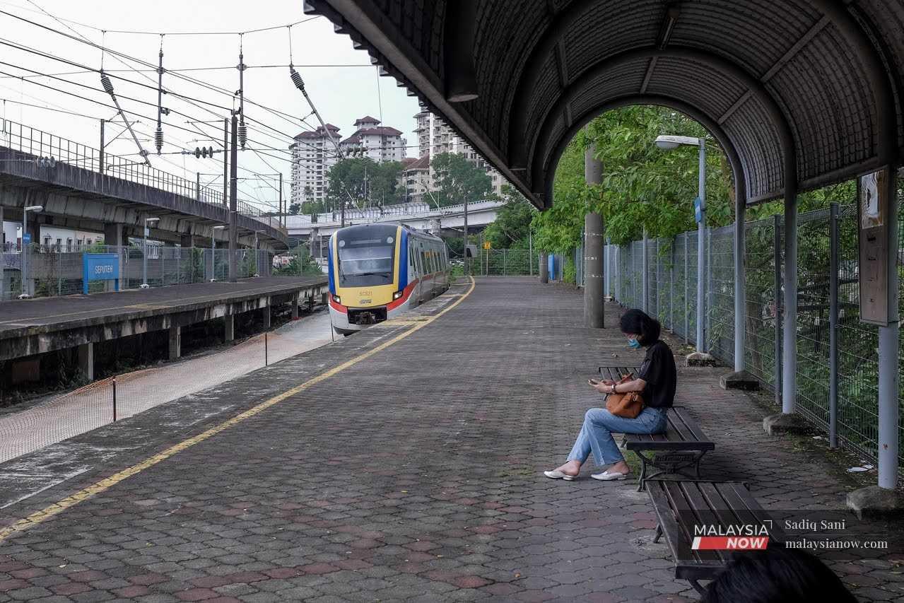 Seorang wanita menunggu tren sampai di stesen KTM Komuter Seputih.