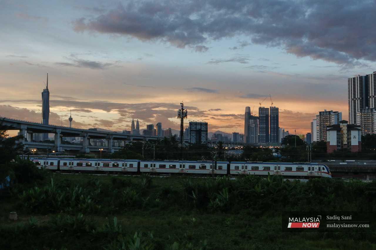 A KTM train passes through the capital city of Kuala Lumpur at nightfall. 