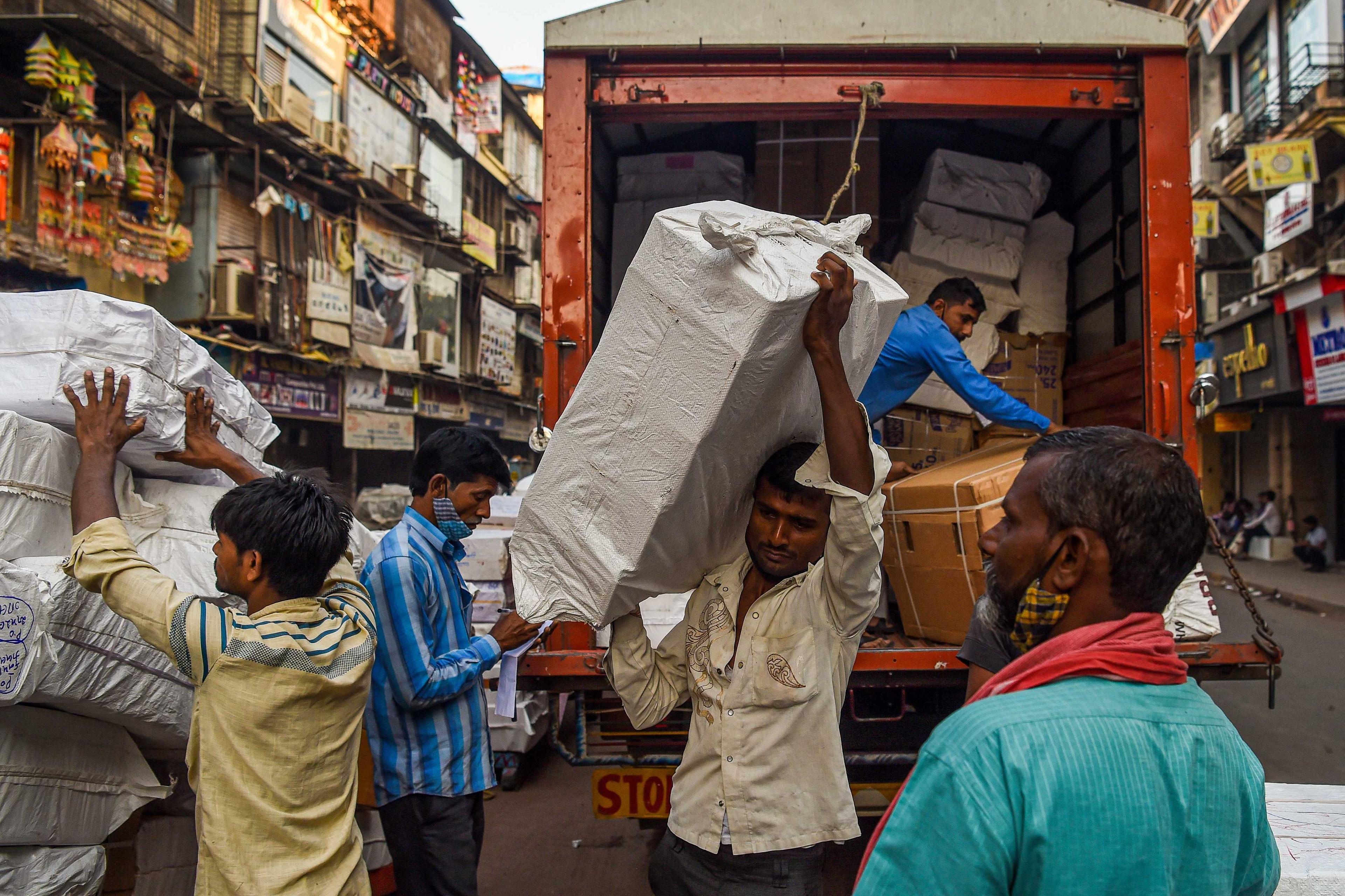 Daily wage workers unload boxes during early morning at a wholesale market in Mumbai on Feb 1. Photo: AFP 