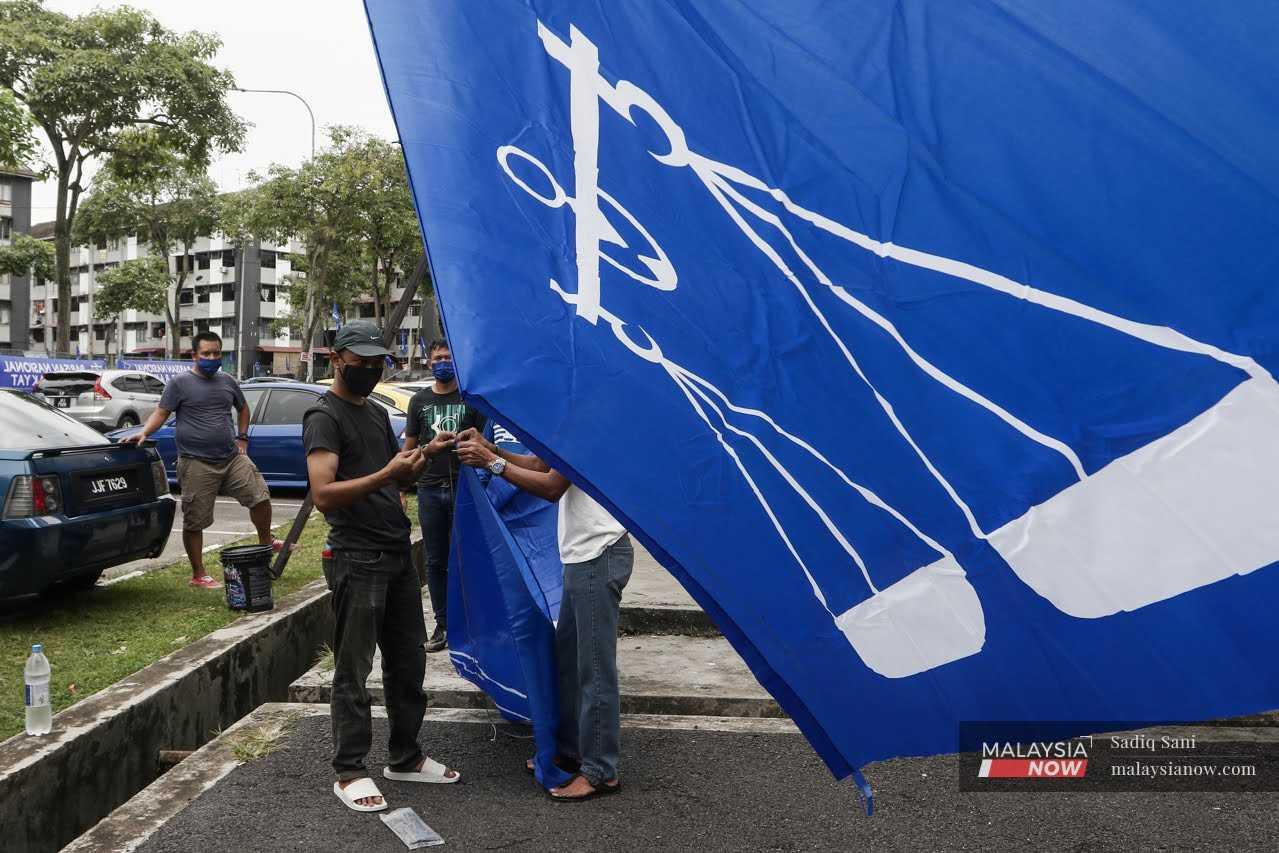 Sukarelawan mengangkat bendera Barisan Nasional di Taman Stulang Laut, Johor Bahru menjelang PIlihan Raya Negeri Johor pada Mac lalu.