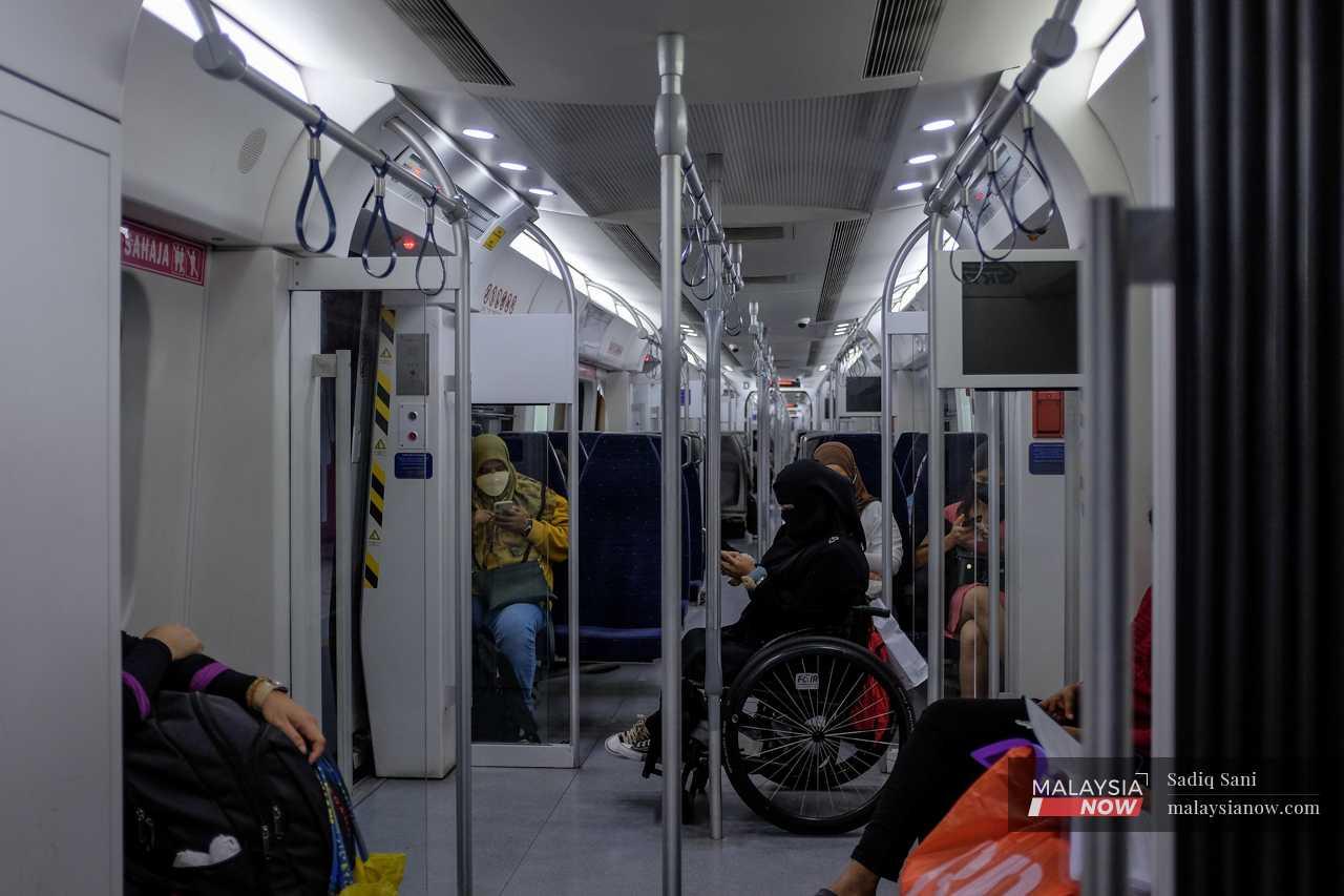 Seorang wanita berkerusi roda memeriksa telefon dalam tren.