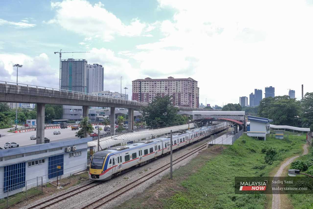 A train makes its way through the Kampung Dato Harun station, next to the NPE highway.