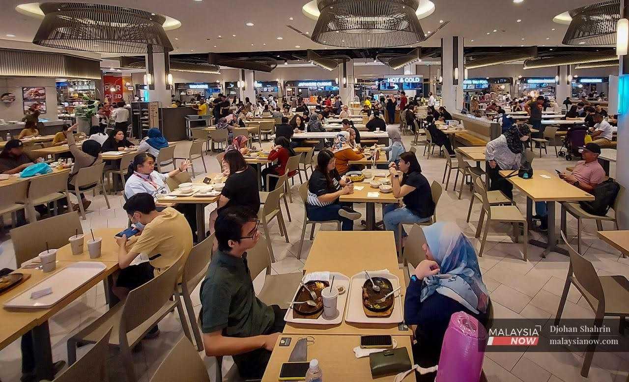 Customers chat as they enjoy a meal at the food court of a mall in Bukit Bintang, Kuala Lumpur.