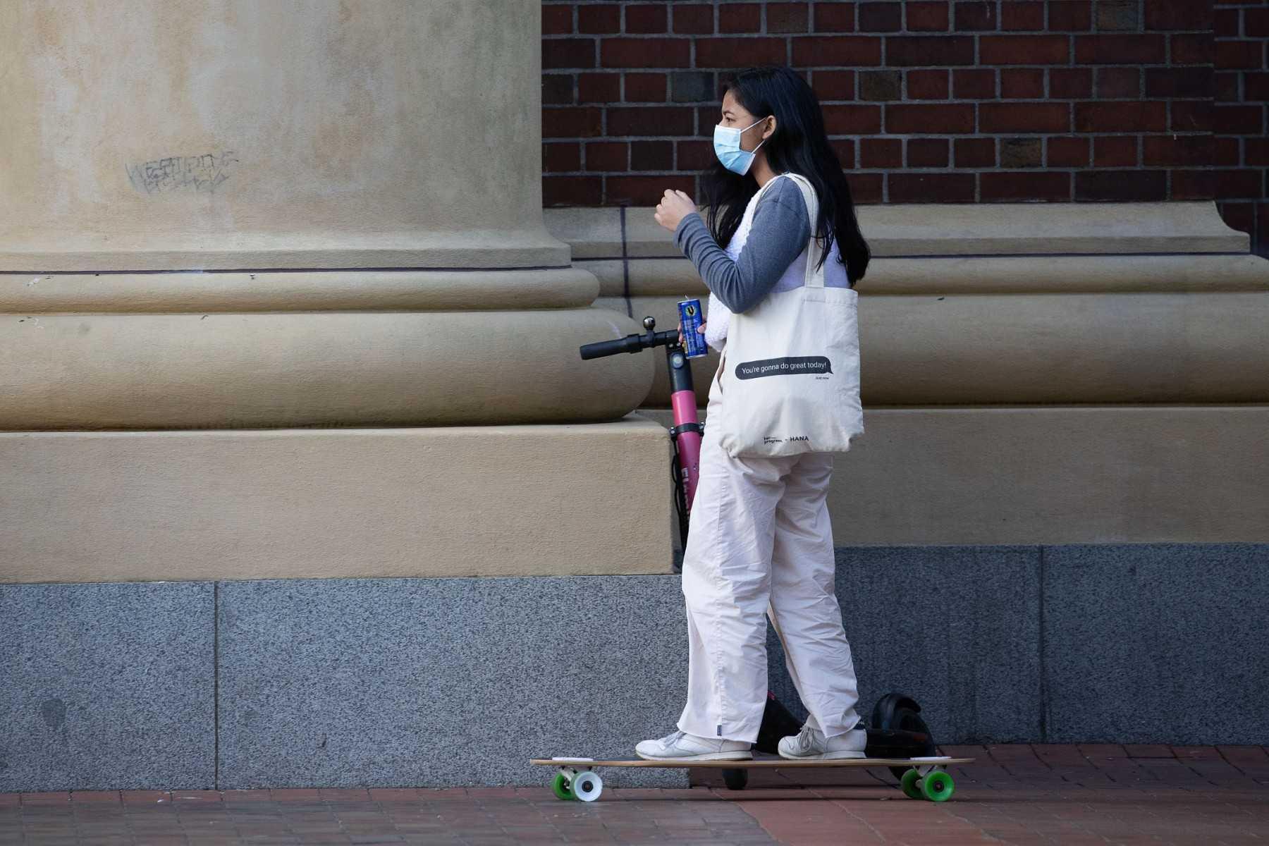 A face mask-clad commuter rides a skateboard in Wellington's central business district in on Aug 12, 2020. Photo: AFP 