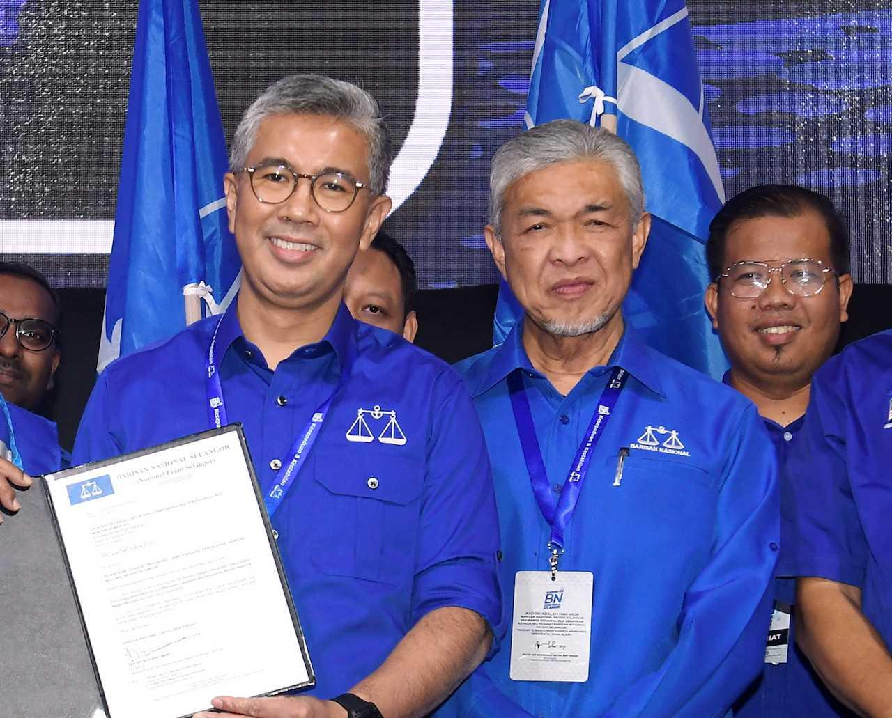 Finance Minister Tengku Zafrul Aziz (left) receives the letter of appointment as Selangor Barisan Nasional treasurer, flanked by BN chairman Ahmad Zahid Hamidi at the closing ceremony of the coalition's convention in Shah Alam on July 31. Photo: Bernama
