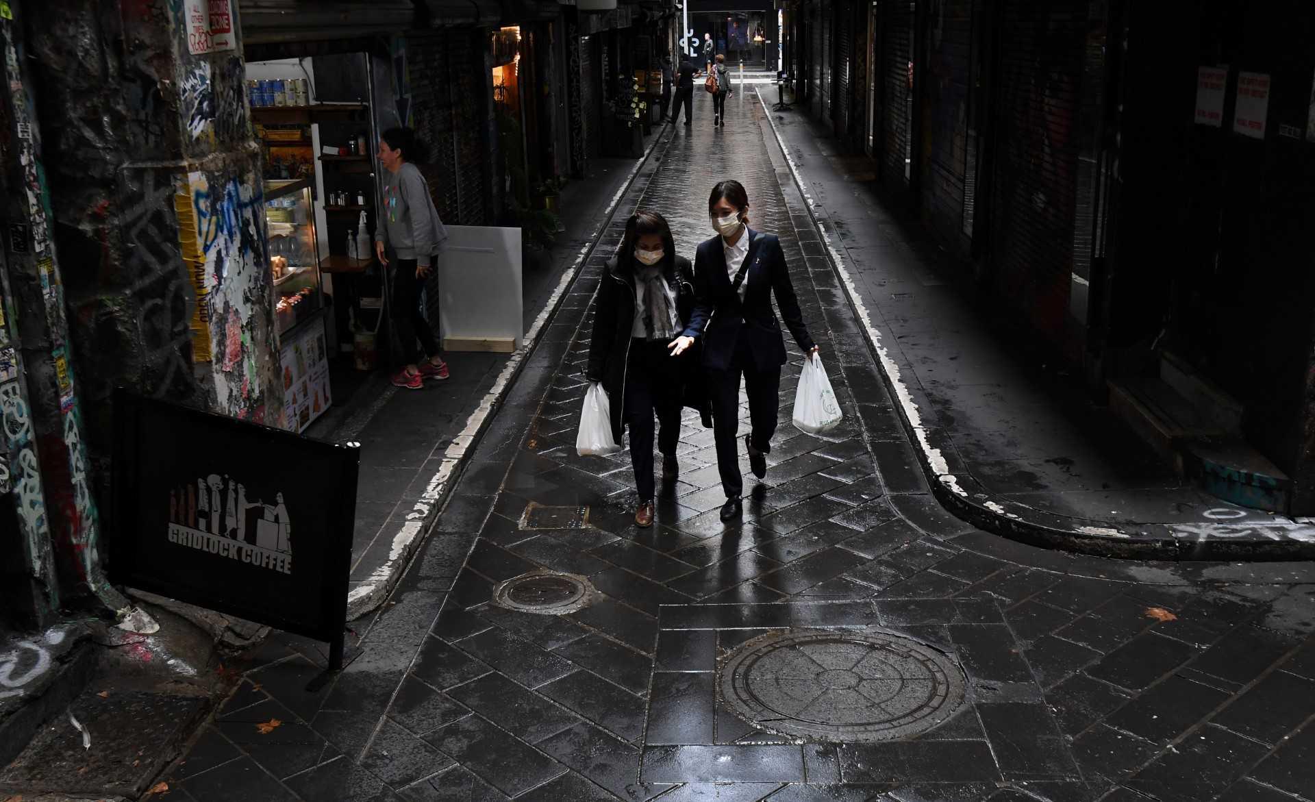 People walk through a small deserted laneway usually packed with open cafes and people during their lunchtime in Melbourne on May 4, 2020. Photo: AFP