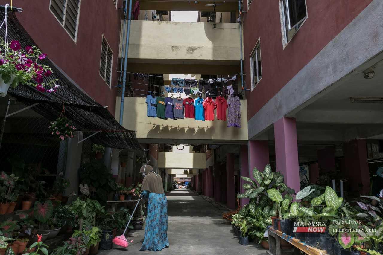 A woman sweeps the floor outside her housing unit at a low-cost flat in Shah Alam.