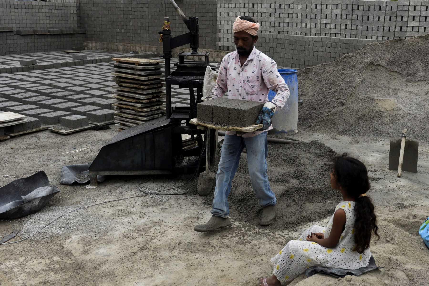 A labourer carries cement bricks to dry at a manufacturing unit on the outskirts of Hyderabad on Jan 15. Photo: AFP