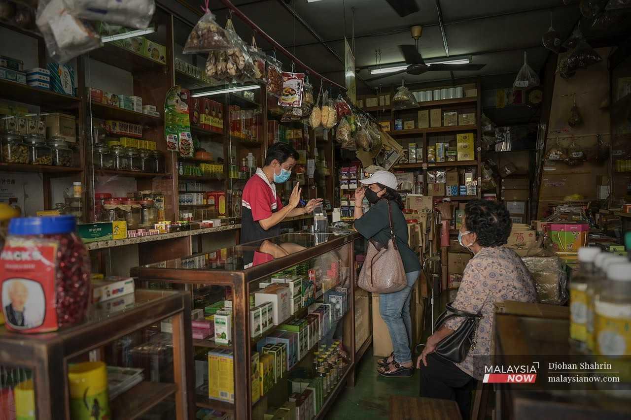 Seorang peniaga kedai ubat herba Cina menerangkan kepada pelanggan mengenai ubat yang mereka ambil di Jalan Carpenter, Kuching.
