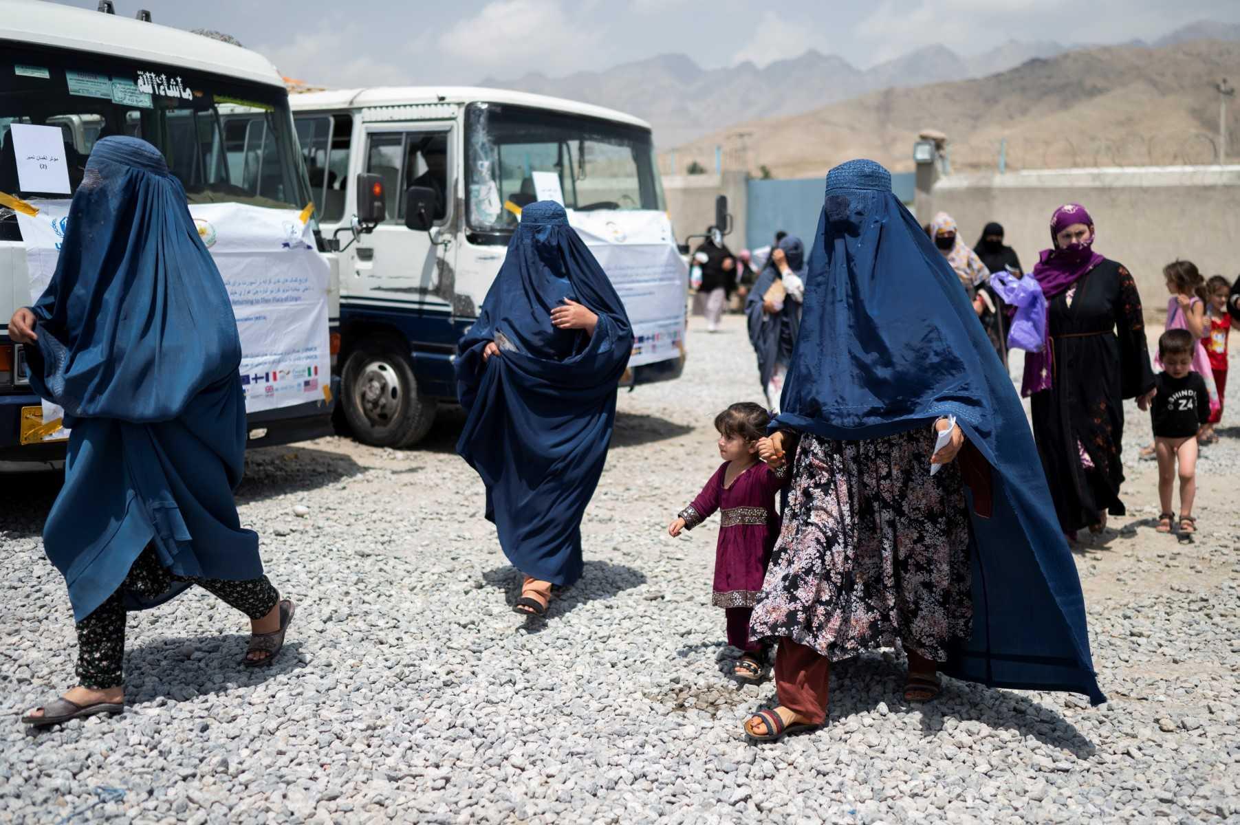 Afghan internally displaced refugee women walk with their children to the bus as they return home to the east, at the United Nations High Commissioner for Refugees (UNHCR) camp in the outskirts of Kabul on July 28. Photo: AFP 