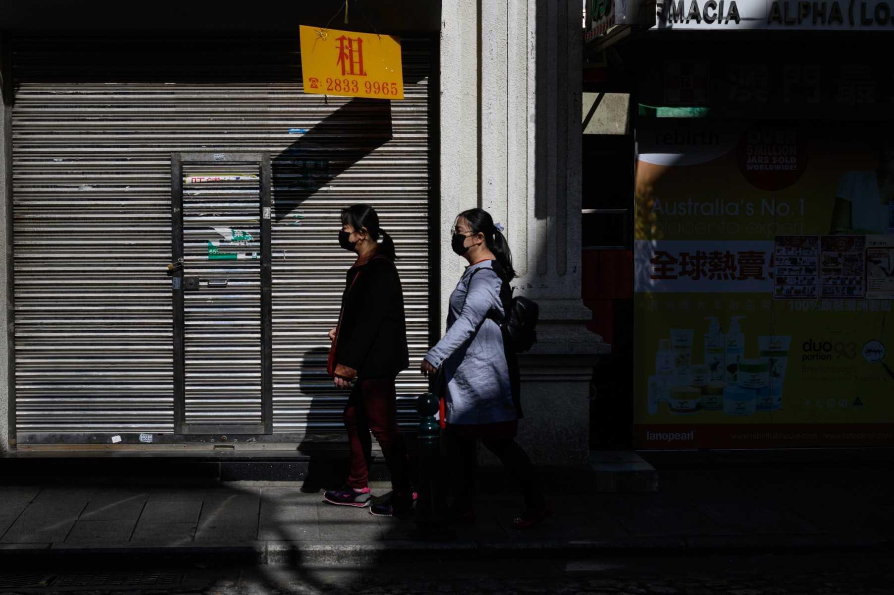 A closed vacant shop (L) is seen as pedestrian wearing facemasks walk by in Macau on Jan 30, 2020. Photo: AFP