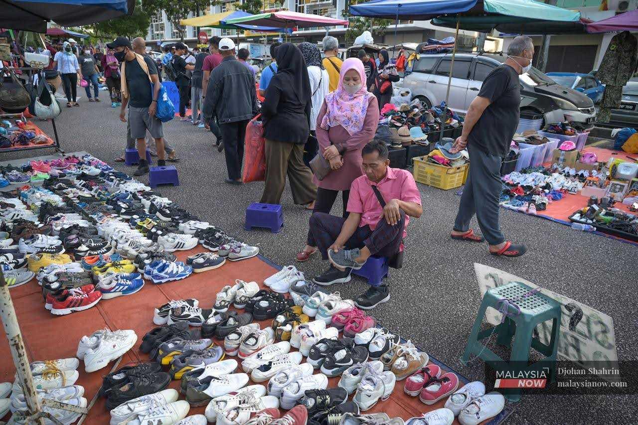 Seorang pelanggan mencuba kasut di pasar barangan terpakai di Kota Damansara, Selangor.