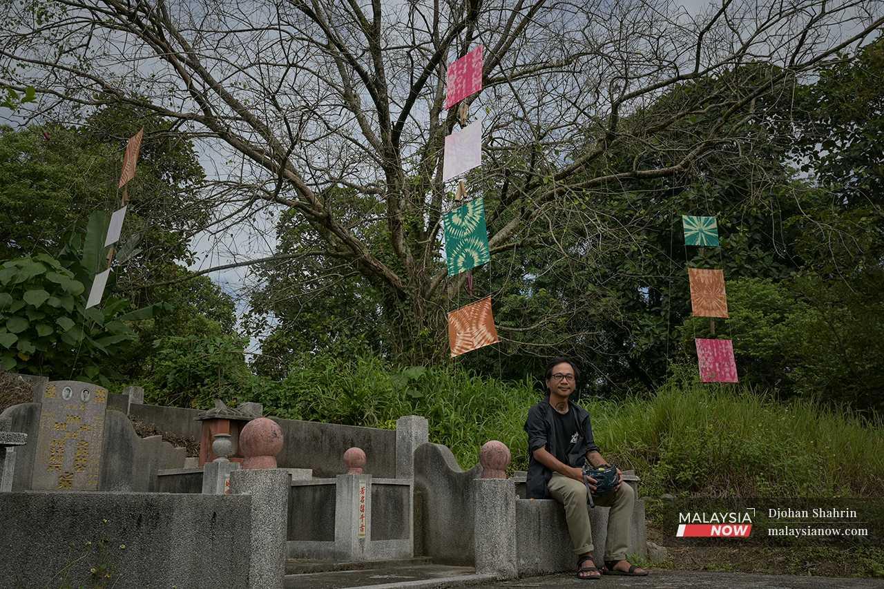 Ahlan, the artist behind the 'Lost Sound' pieces, sits on the edge of a tombstone under one of his artworks. 