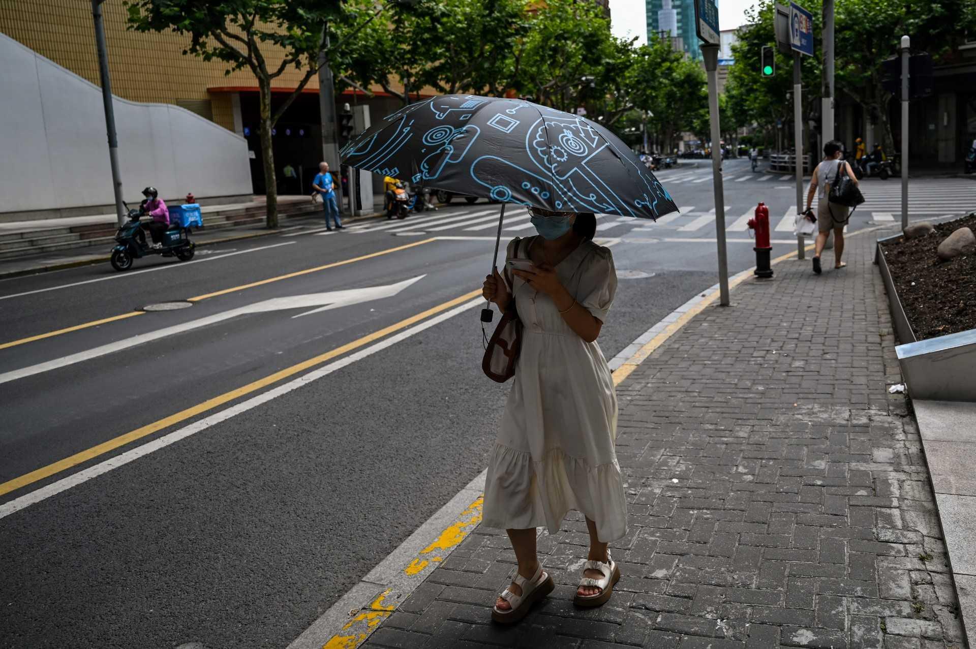A woman walks on a street protecting herself from the sun with an umbrella in the Jing'an district of Shanghai on July 11. Photo: AFP