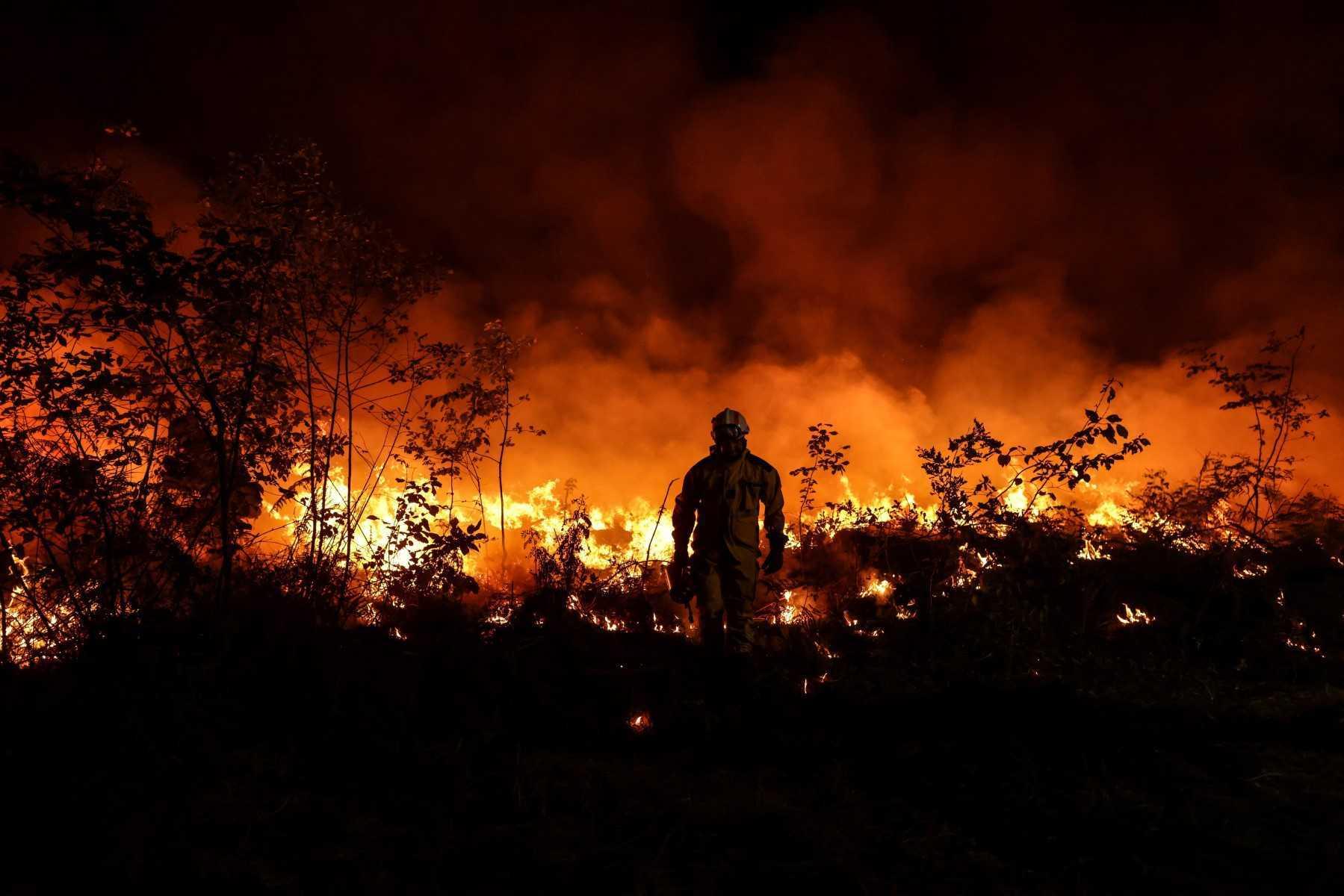 A tactical firefighter set fires to burn a plot of land as firefighters attempt to prevent the wild fire from spreading due to wind change, as they fight a forest fire near Louchats in Gironde, southwestern France on July 17. Photo: AFP