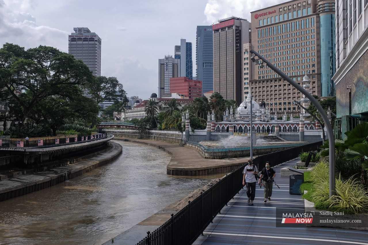Dua warga kota berjalan di laluan pejalan kaki pusat bandar Kuala Lumpur. 