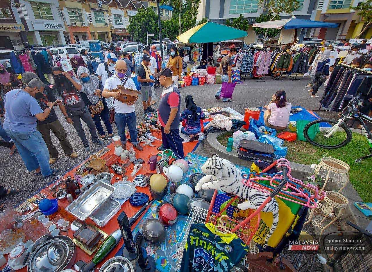Seorang pengunjung pasar barangan terpakai di Kota Damansara, Selangor tawar menawar dengan seorang penjual.