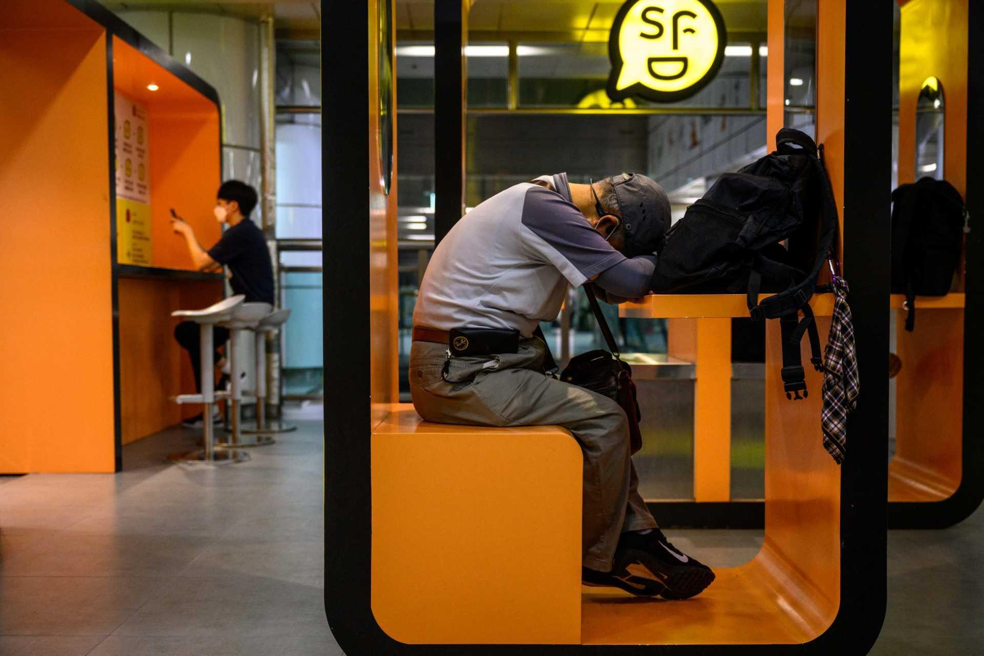 A man sleeps at a cubicle in an area for relaxing, charging electronic device batteries or desk work, in a metro underground train station in the Gangnam district of Seoul on Aug 12. Photo: AFP 