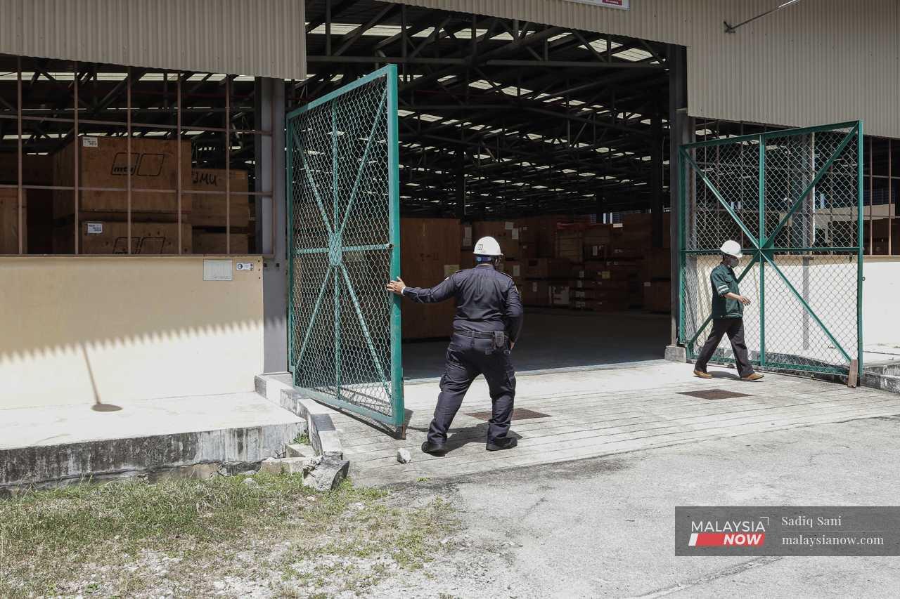 Pegawai menutup pintu pagar salah satu gudang di mana peralatan untuk pembinaan LCS disimpan.