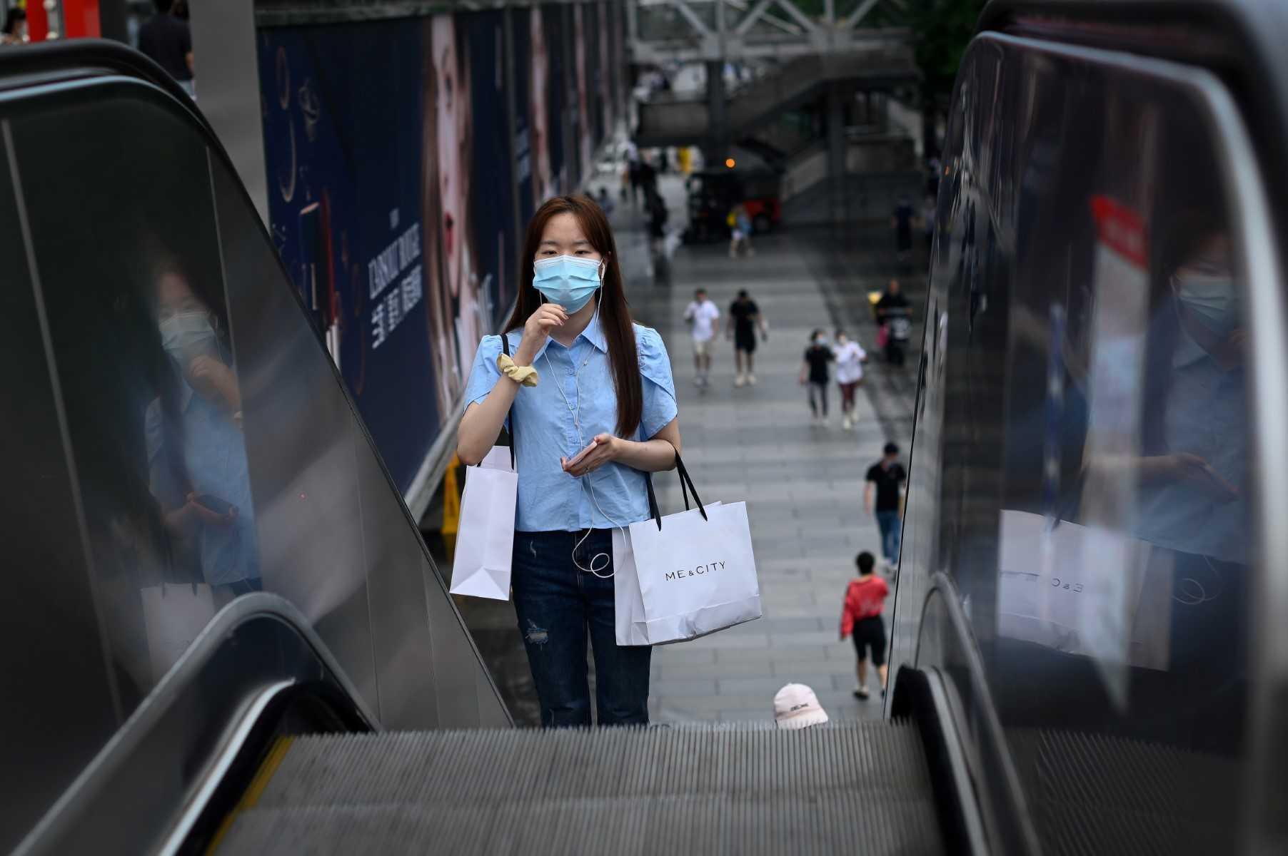 A woman rides an escalator outside a mall in Beijing on July 12. Photo: AFP