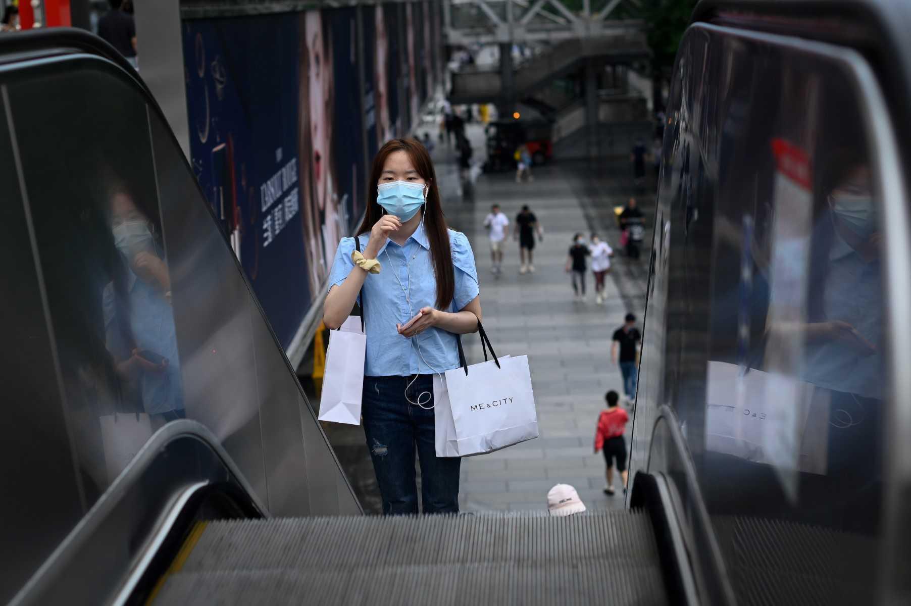 A woman rides an escalator outside a mall in Beijing on July 12. Photo: AFP 