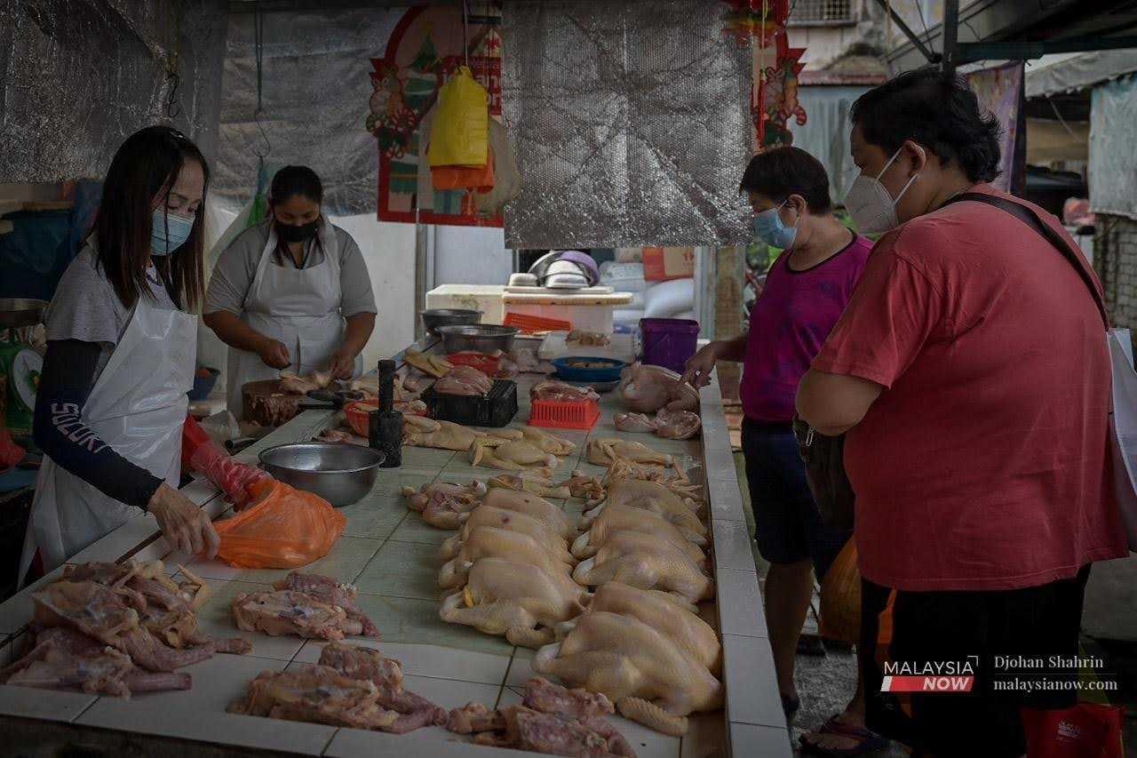 Customers choose some chicken at a poultry stall at Pasar Ampang in Selangor.