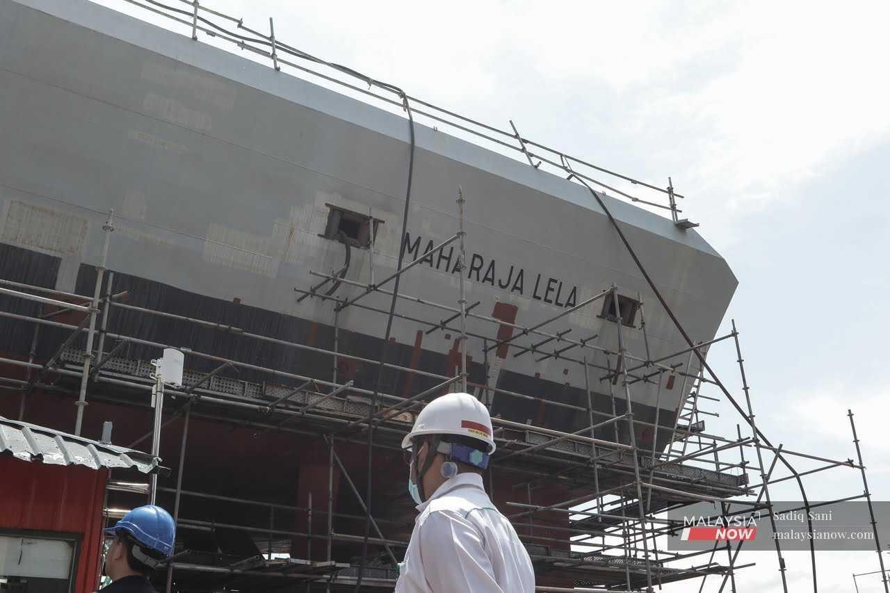 A worker looks at the KD Maharaja Lela, one of the littoral combat ships supposed to be delivered to the navy but which has fallen behind schedule, at the Boustead Naval Shipyard in Lumut, Perak. 
