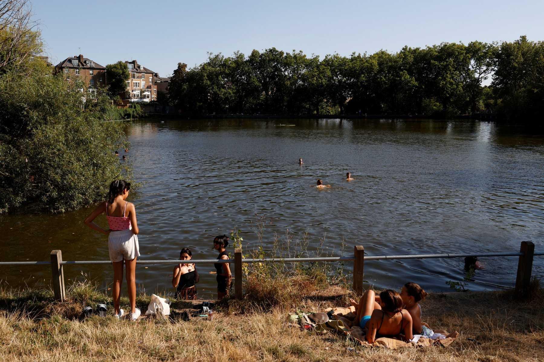 People have a swim on a pond in Hampstead Heath park to cool off from the heat, in London, on Aug 13. Photo: AFP 