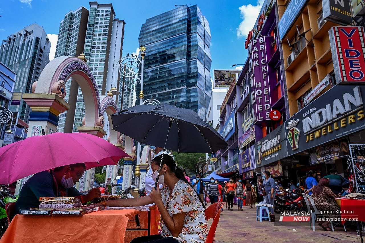 Pelukis inai memberikan khidmat kepada pelanggannya di Brickfields, Kuala Lumpur.

