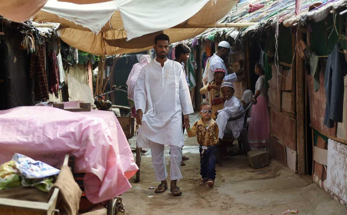 A Rohingya man walks with his son at a slum village in New Delhi, July 7, 2016. Photo: AFP