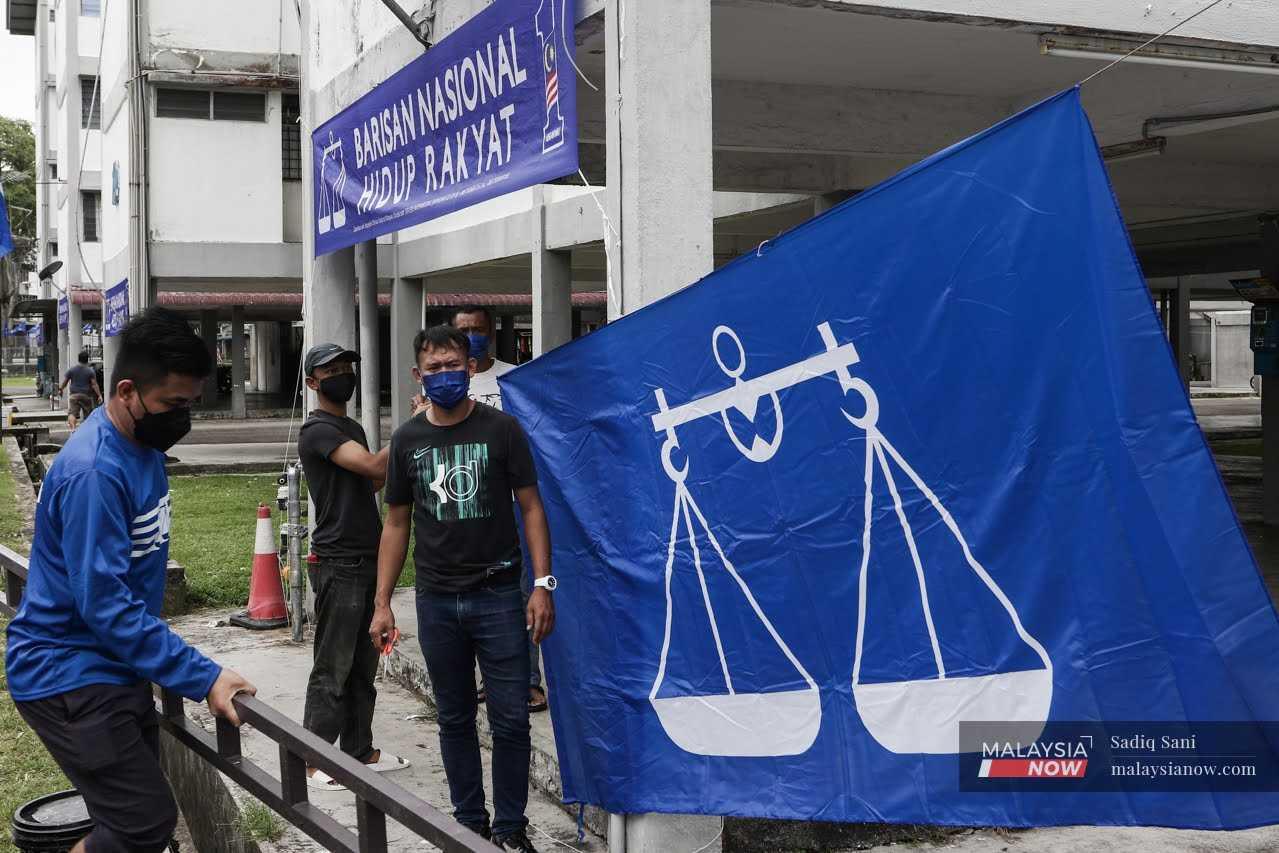 Volunteers from Barisan Nasional hang a giant party flag at an apartment block in Taman Stulang Laut, Johor Bahru, ahead of the state election in March.
