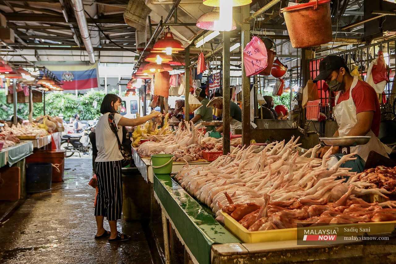 A woman chooses fresh chicken from a poultry stall at Pasar Raja Bot in Kuala Lumpur.