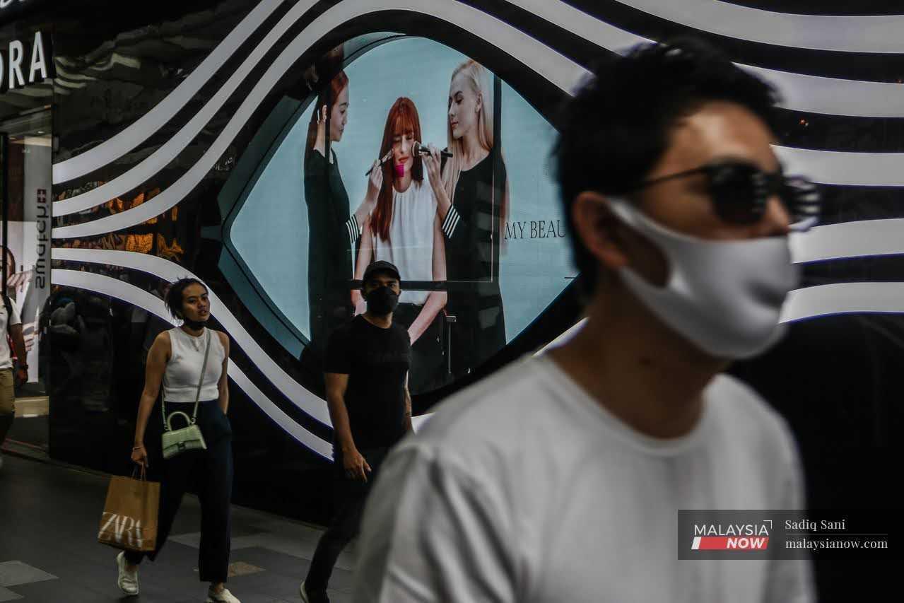 Orang ramai memakai pelitup muka ketika berjalan di kawasan pusat bandar Kuala Lumpur bagi mengelak jangkitan Covid-19.