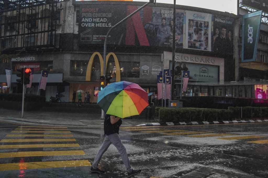 Soerang lelaki meredah hujan di pusat bandar Kuala Lumpur. Pakar berkata pencemaran air hujan harus menjadi amaran kepada negara dalam usaha menanganinya.