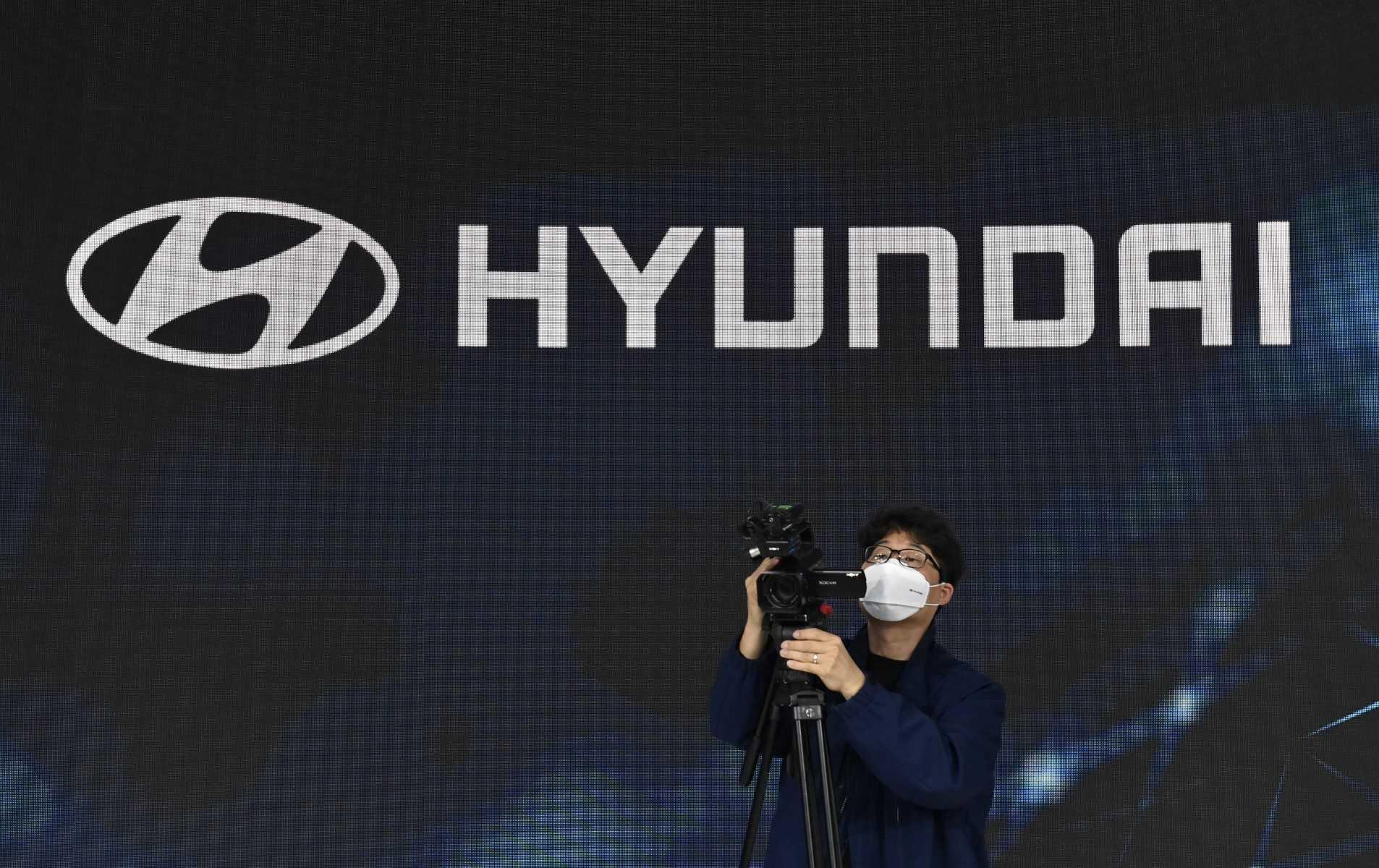 A man takes video footage in front of the logo of South Korean auto-maker Hyundai Motor in Goyang on Nov 25, 2021. Photo: AFP