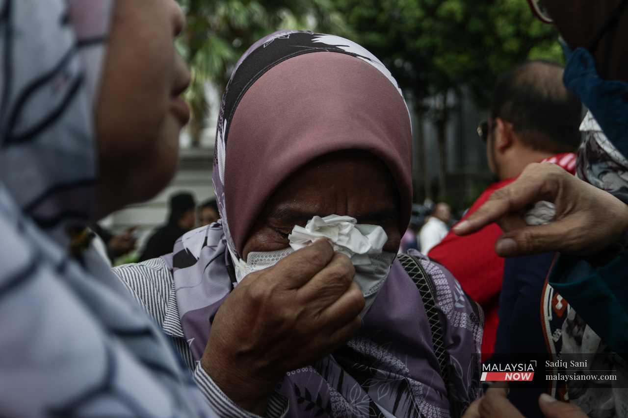 Outside the court complex, a woman cries after learning the court's decision to uphold Najib's conviction and sentence. 
