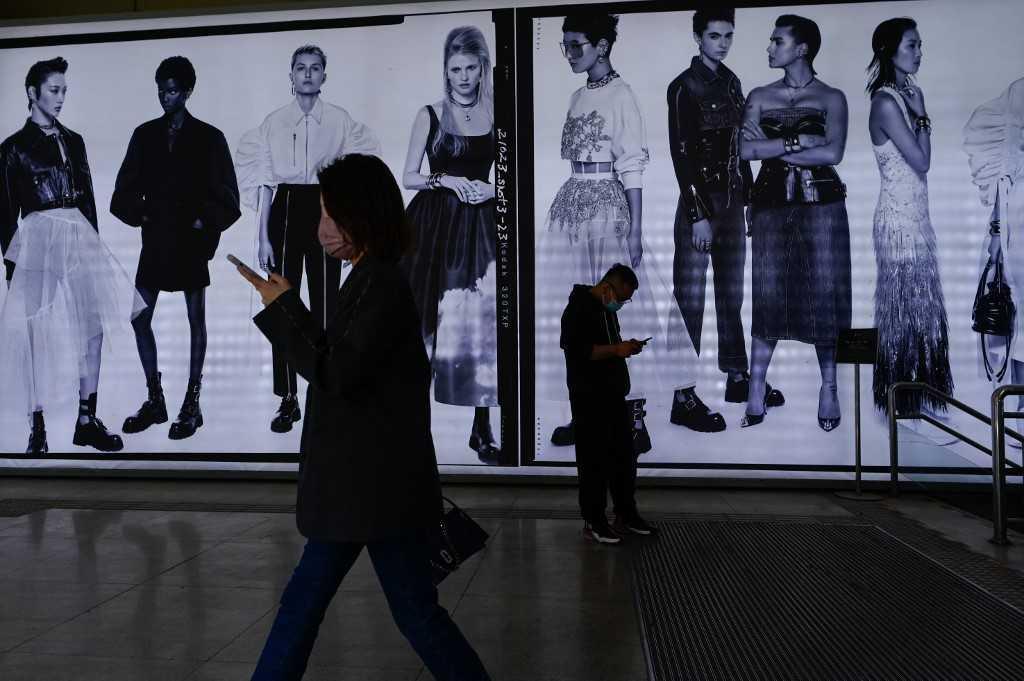 People walk past an advertisement in Beijing on April 14. Photo: AFP 